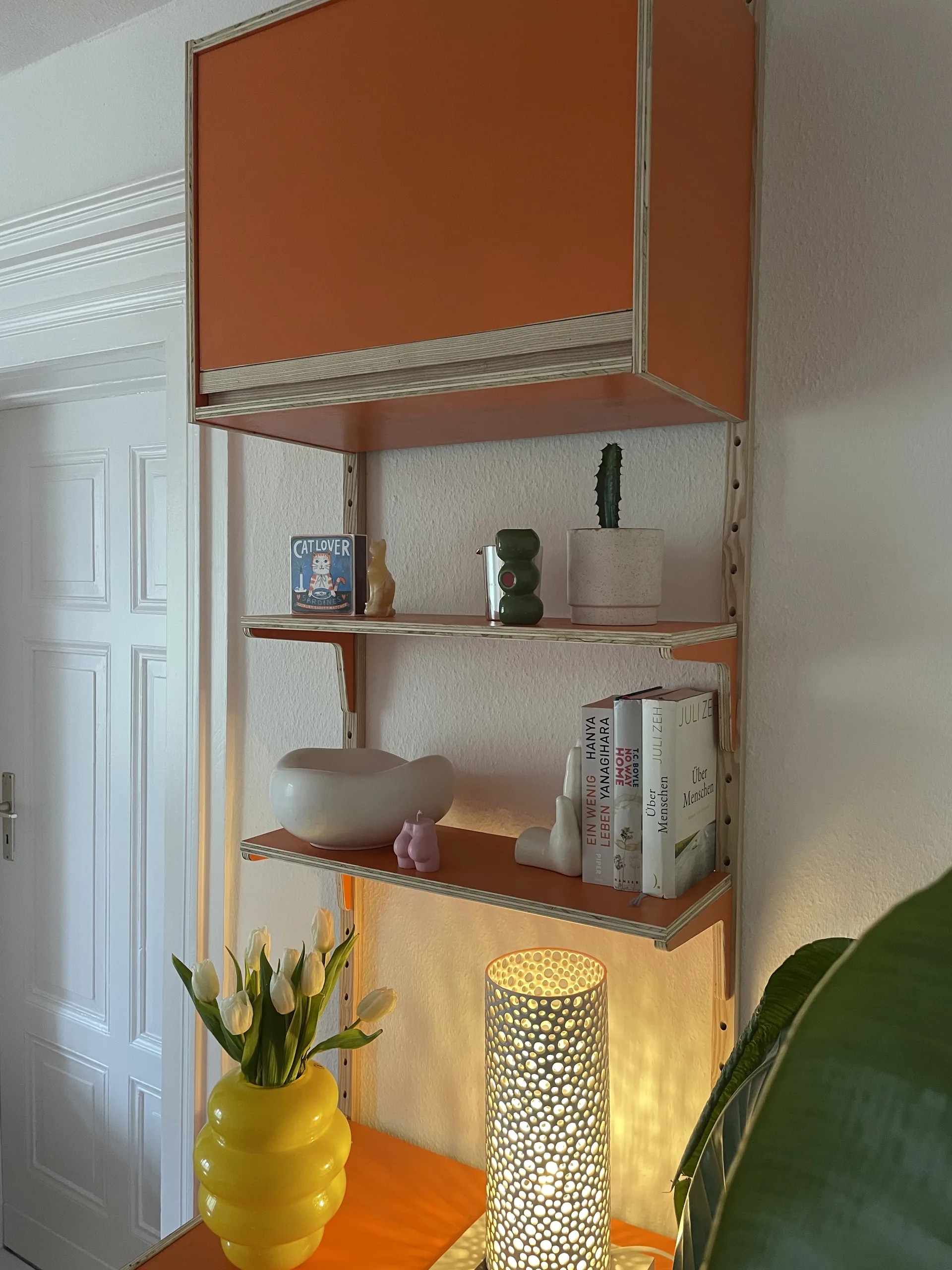 VITIS Orange — Detail der Klappenmodule und Winkelböden mit Stillleben aus Tulpen, Büchern und perforierter Designlampe